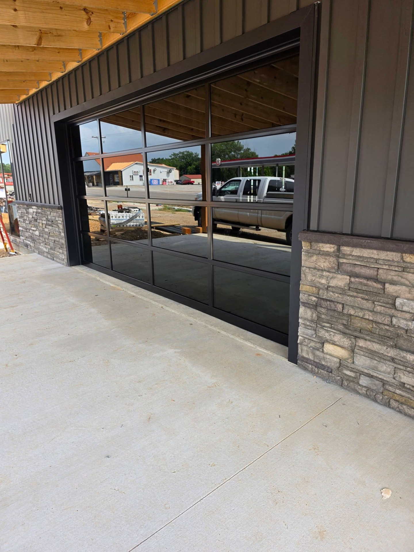 Driftwood exterior on Main Street in Warsaw, Missouri — black glass garage door and stone facade